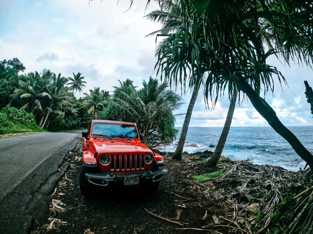 Red Jeep parked at a tropical shore